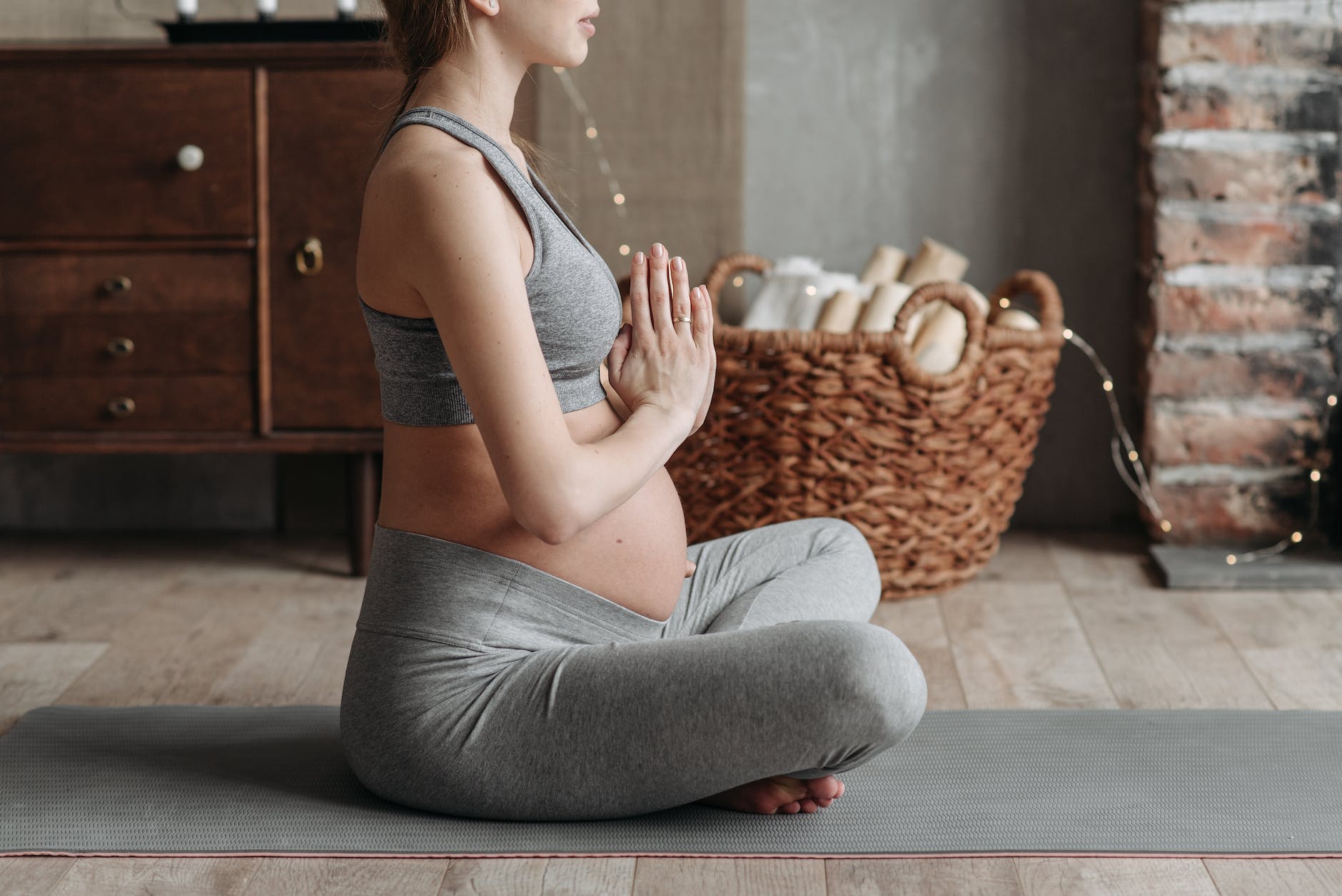 a pregnant woman wearing gray tank top meditating