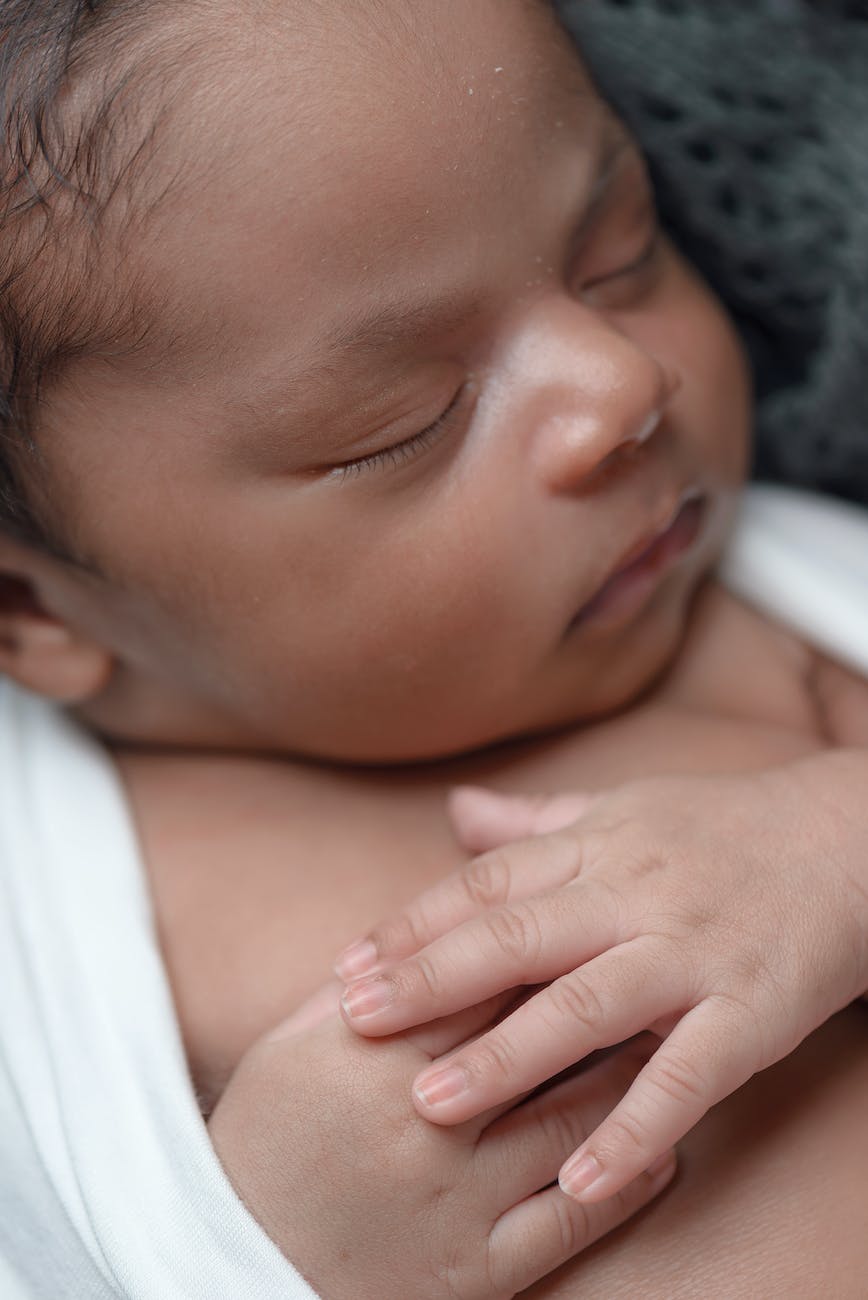 baby sleeping while covered white coat